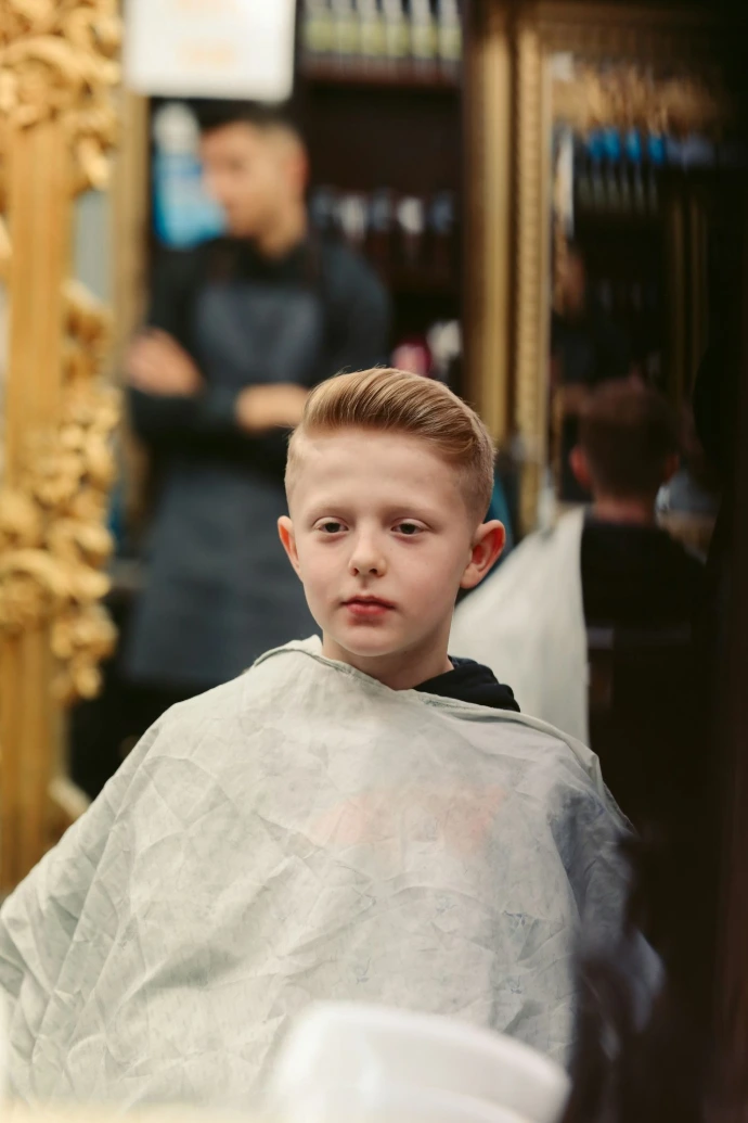 en ung dreng der får klippet hår i en barbershop